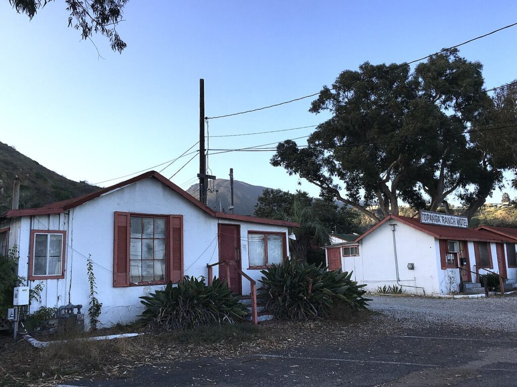 The Topanga Ranch Motel buildings at dusk, with hand-painted sign visible against the Santa Monica Mountains